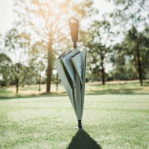 Inverted umbrella standing upright on grass with trees in the background