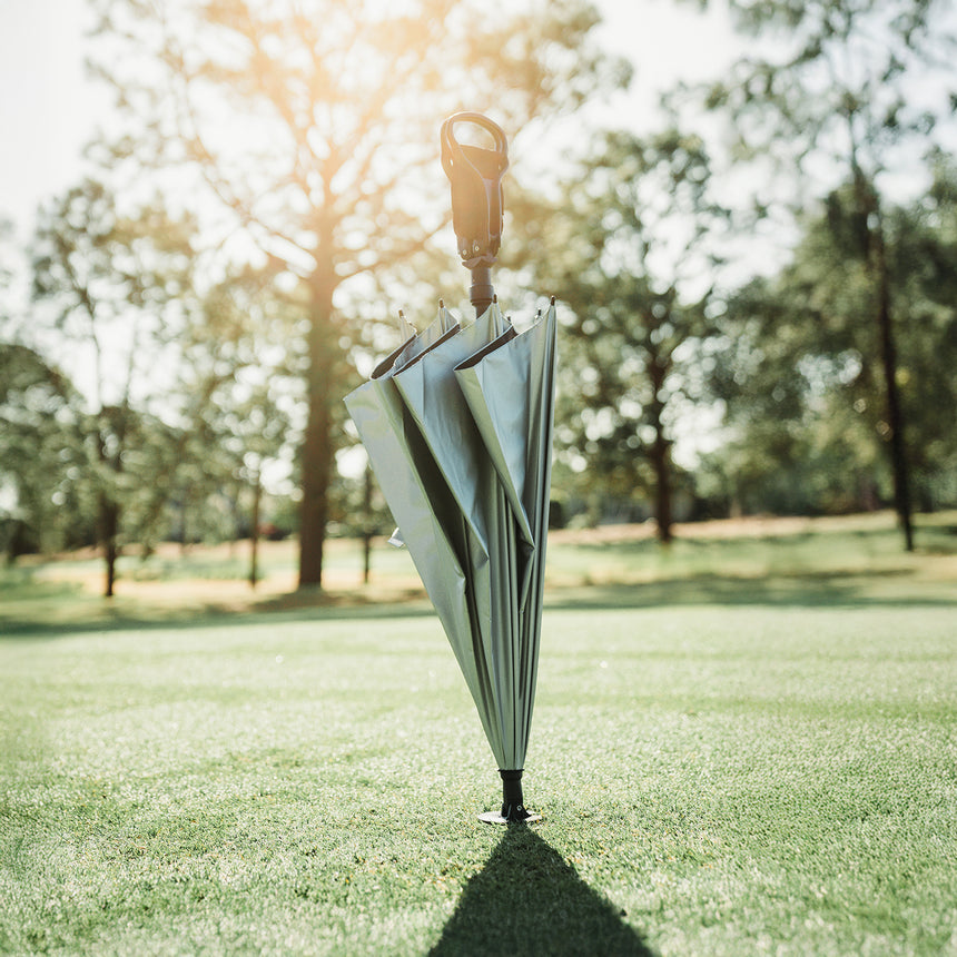 Inverted umbrella standing upright on grass with trees in the background